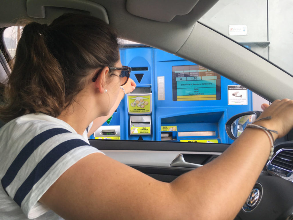 Donna intenta a pagare il pedaggio autostrada alla cassa automatica