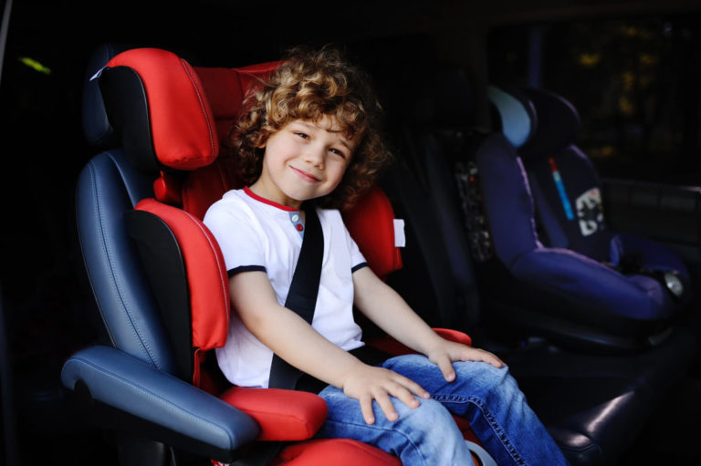 Bambino viaggia nel seggiolino auto con rialzo e cintura di sicurezza allacciata
