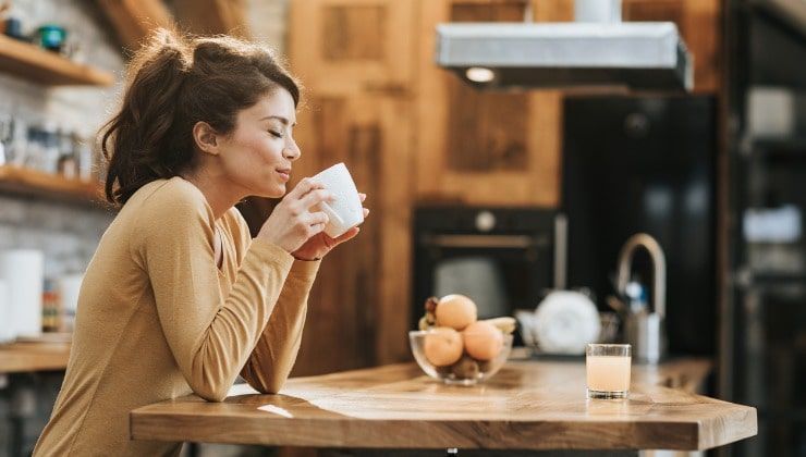 giovane assapora il caffe in cucina