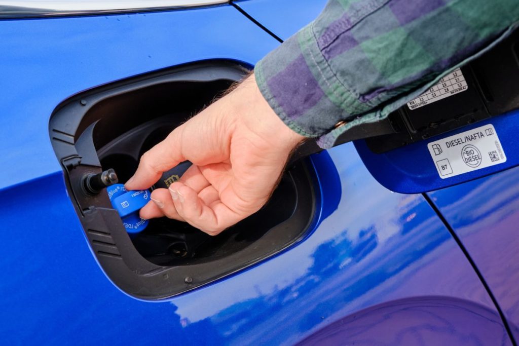 Automobilista effettua rabbocco AdBlue nel serbatoio auto.jpg
