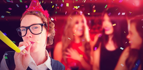 person in nerdy glasses and shirt with a party hat on blowing a party horn with three people chatting in the background image has a confetti overlay m.png