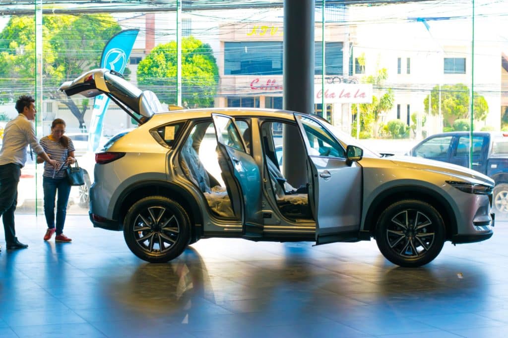 Venditore mostra auto nuova a un cliente in una concessionaria del Giappone.jpg