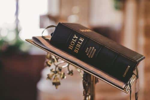 a black bound copy of the bible on a stand adorned with golden vines m.jpg