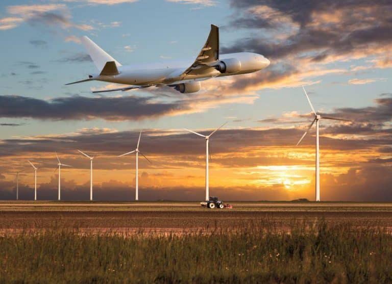 plane takes off above a farm field and wind electric generators m.jpg