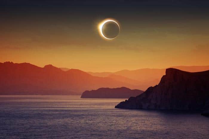 solar eclipse over a yellow orange sky cliffs and the sea m.jpg