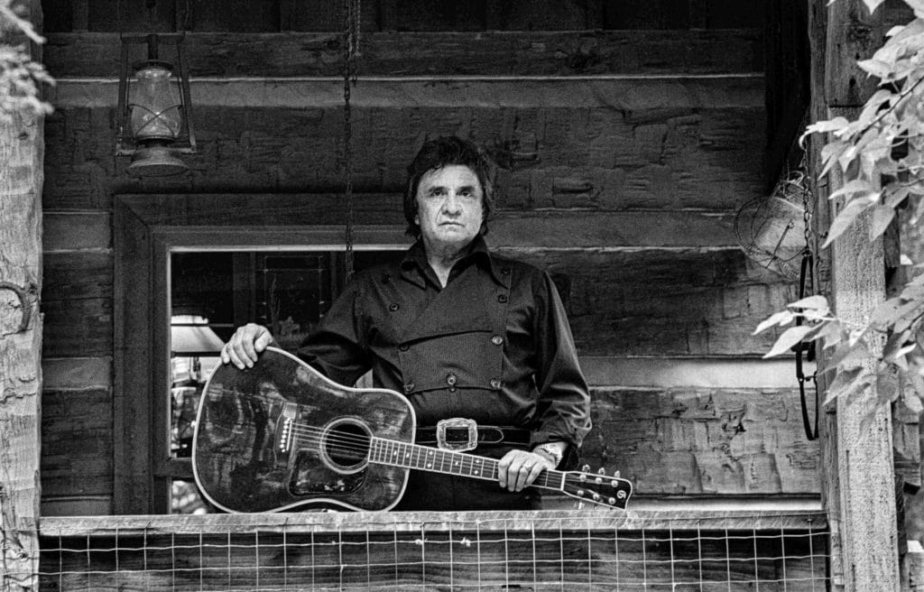 CASHJOHNNYCabinPorchGuitarMay1987croppedCredit Alan Messer scaled.jpg
