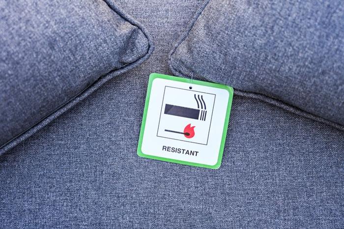 a white square label with a match and a cigarette and the word resistant on a denim sofa m.jpg