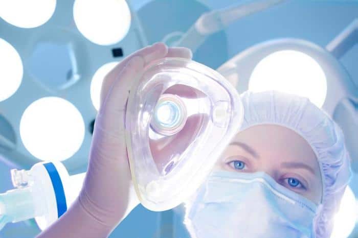 L’Influenza degli Anestetici sulla Percezione del Cervello 1 person in surgical cap and mask lowering a surgical gas mask down towards the camera m 1.jpg
