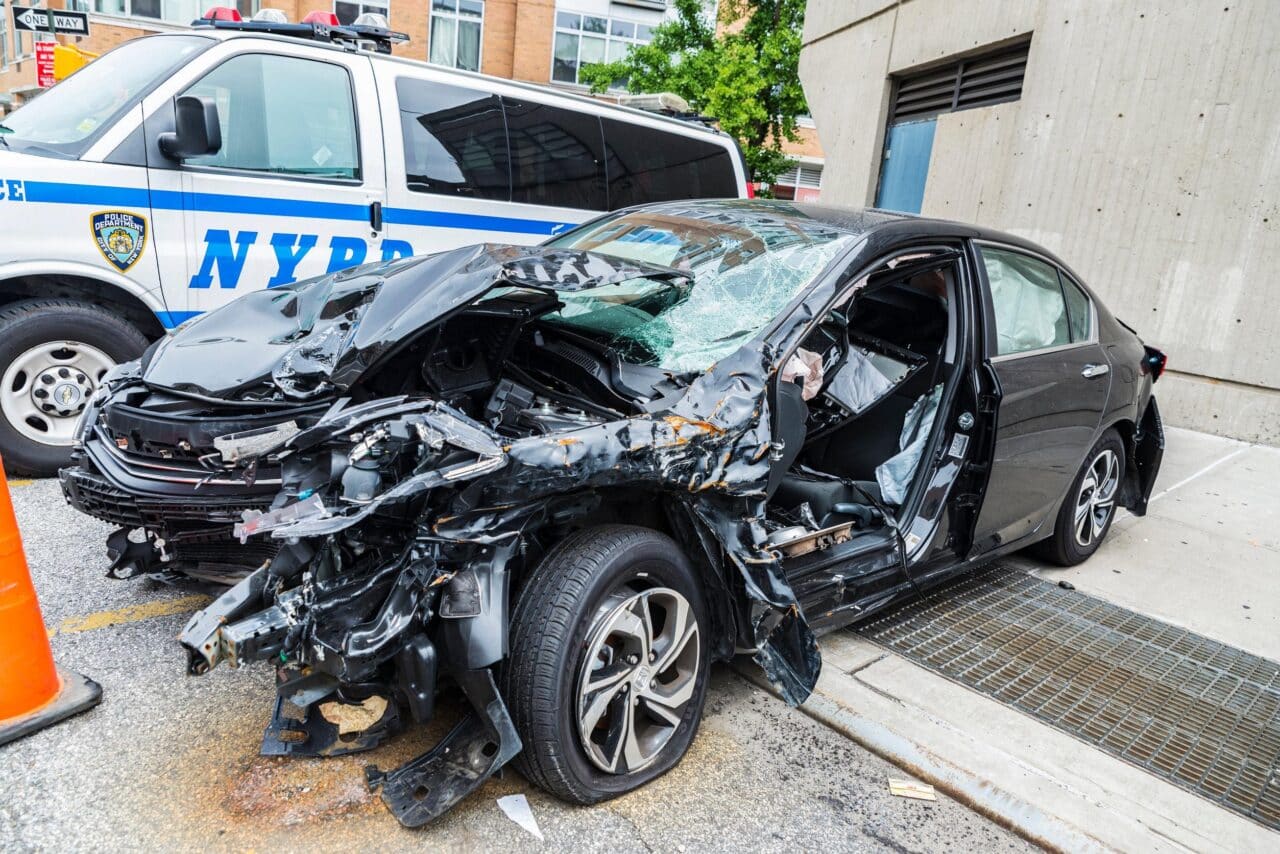 Auto dopo incidente stradale accanto a vettura polizia USA e1734345117818.jpg